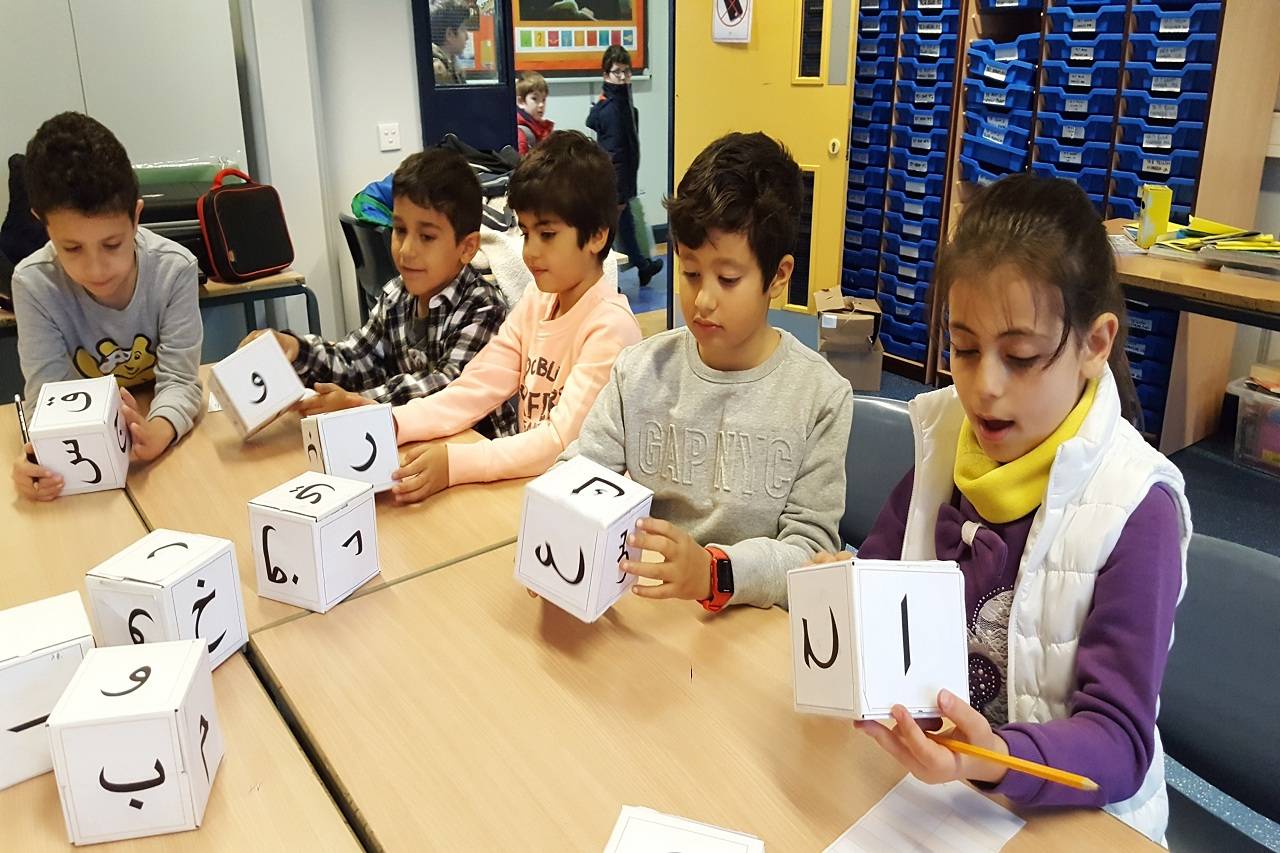 % or 6 children are holding cubes with Aranbic letters and trying to learning Arabic.