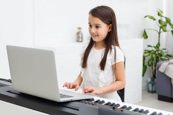 In this image a girl is learning to play Piano