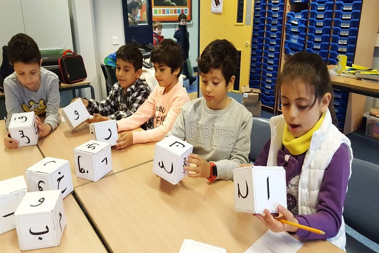 % or 6 children are holding cubes with Aranbic letters and trying to learning Arabic.
